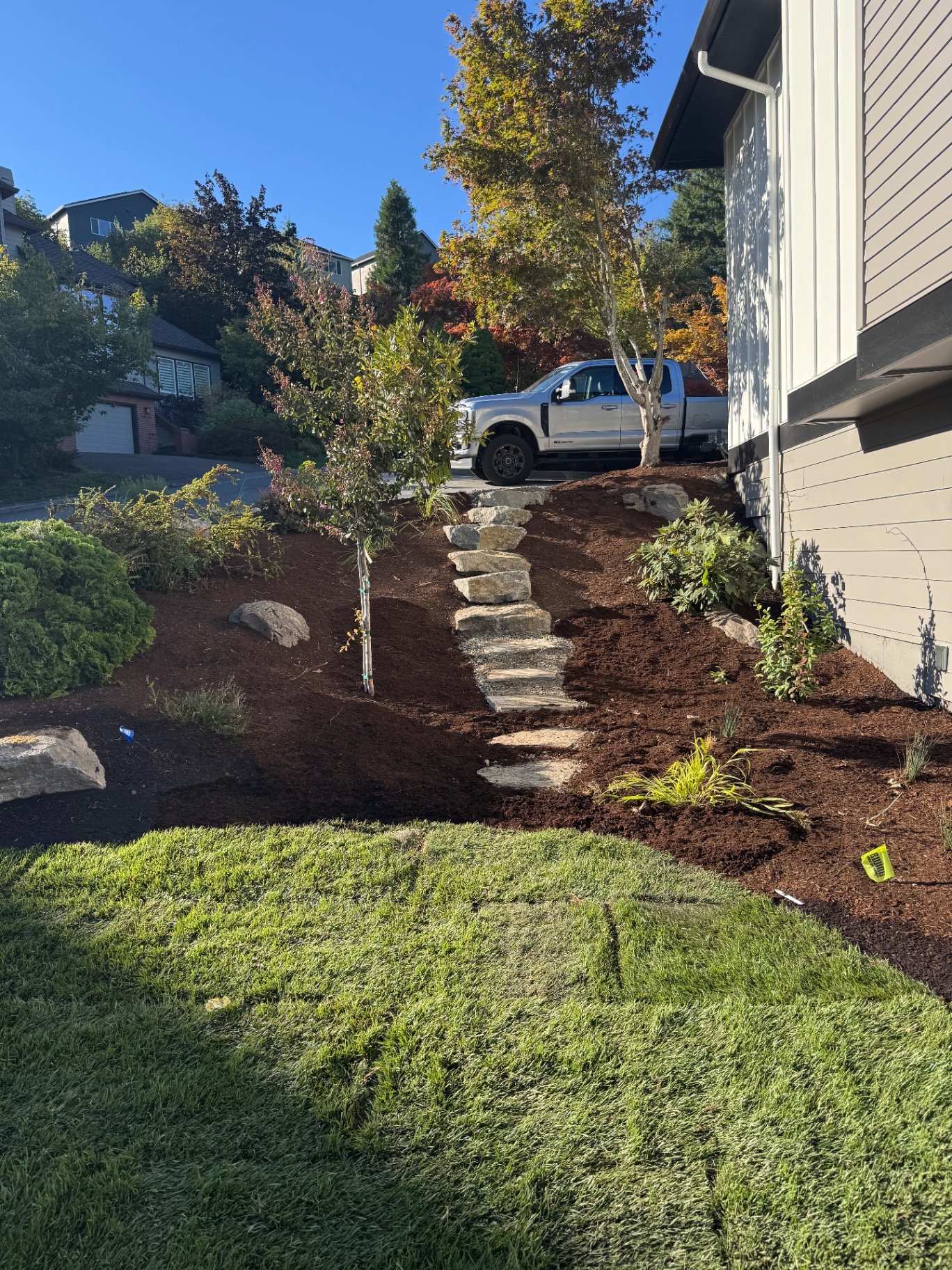 Mulched landscape with stone path and fresh sod by Ernest Landscape